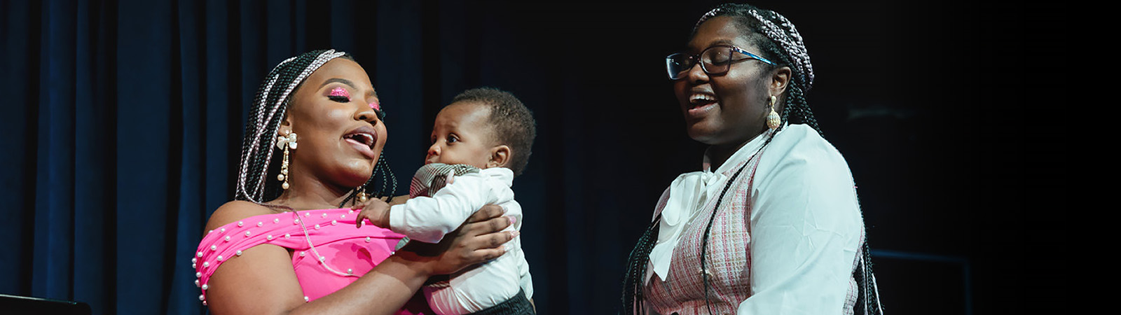 two mothers singing, one is holding a small baby
