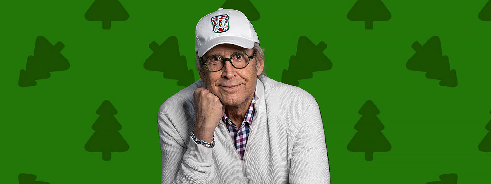 Chevy Chase smiling in a white hat and glasses
